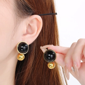 Close-up of vintage black round gemstone earrings with gold metal ball detail on ear