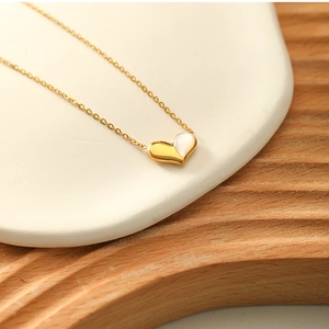 Close-up of heart necklace with gold chain and mother of pearl inlay on a beige plate