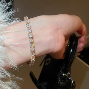 Close-up of sparkling tennis bracelet with square zircons worn on wrist with elegant accessories