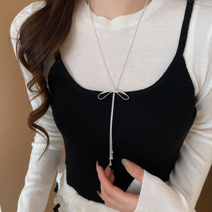 Détail du collier pendentif nœud argenté sur un mannequin avec un éclat métallique