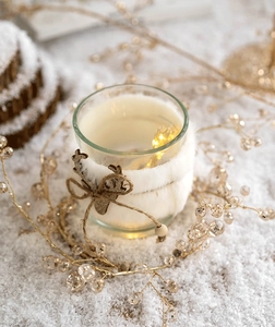 Close-up of Christmas glass candle holder with reindeer charm and warm LED lighting