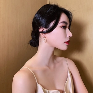 Close-up of elegant gold beaded pearl hoop earrings worn by a model in soft lighting