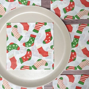 Christmas stocking print paper napkins set on a plate over wooden background