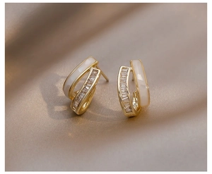 Makroansicht goldener C-förmiger Vintage-Ohrringe mit weißer Emaille und Zirkonia-Steinen