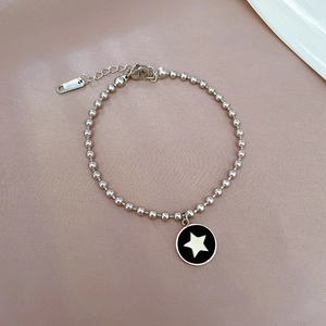 Dettaglio del bracciale di perle in acciaio al titanio con ciondolo a stella nera