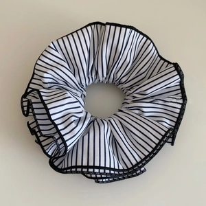 Détail d'un grand chouchou en tissu rayé bleu avec couture noire à bord festonné