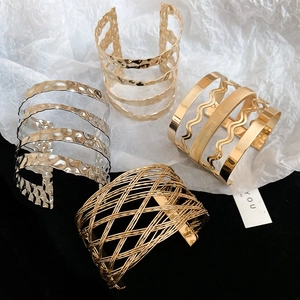 Detail of gold and silver chunky bangles with hammered, wavy, and mesh hollow textures