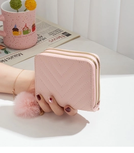Detail of pink double zipper wallet with V-quilt stitching and soft pompom charm