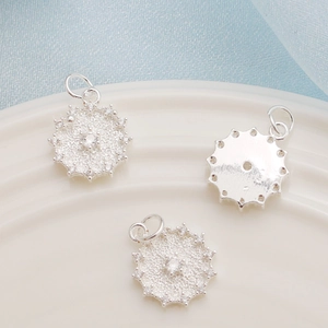 Macro detail of three silver sun-shaped pendants with inlaid cubic zirconia for jewelry