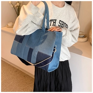 Detail of multi-tone denim patchwork tote bag with cross-body strap on a model