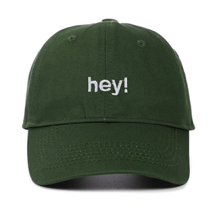 Détail d'une casquette en coton vert foncé avec broderie blanche 'hey!' sur le devant