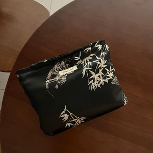 Macro shot of black jacquard bag with golden bamboo pattern and a simple wish label
