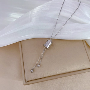 Detail of silver titanium steel necklace with cylindrical pendant and small tassels