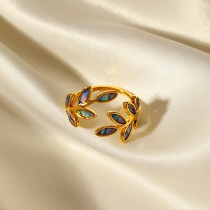 Detailed close-up of golden leaf ring with colorful abalone shell on silk fabric