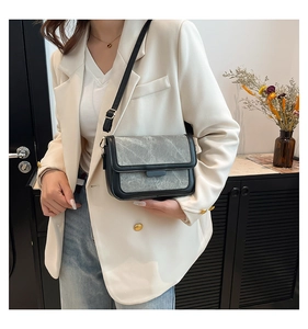 Detail of grey stone texture crossbody bag with black leather trim and adjustable strap