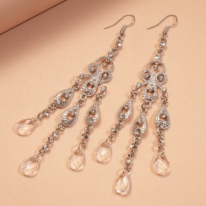 Eleganti orecchini a goccia con nappine argentate, strass e dettagli in vetro su sfondo tenue