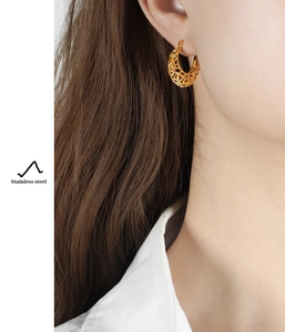 Detail of golden hollow U-shaped stainless steel earrings with honeycomb texture