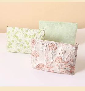 Detailed close-up of three canvas cosmetic bags with exquisite 3D floral embroidery