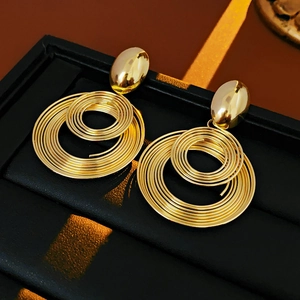 Detailed macro view of intertwined golden circular hoop earrings on a black background