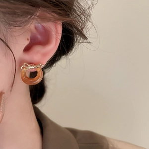 Close-up of vintage bow earrings with amber resin hoop on model side view