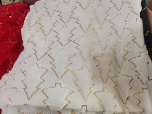 Macro detail of white plush fabric with gold sequin Christmas tree embroidery pattern