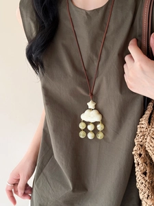 Gros plan du pendentif nuage en résine avec perles sur un collier en cordon brun