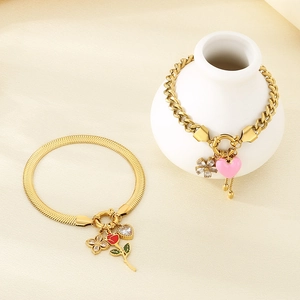 Close-up of golden stainless steel bracelets with pink heart and rose pendants