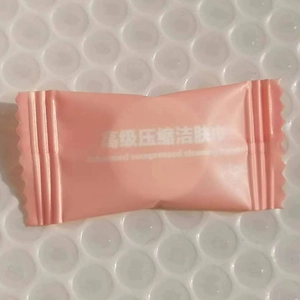 Portable disposable compressed cotton facial towels in individual pink candy packaging