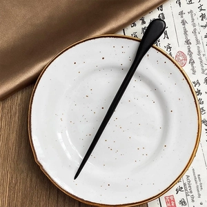 Close-up of a minimalist black wooden hair pin with teardrop design on ceramic tray