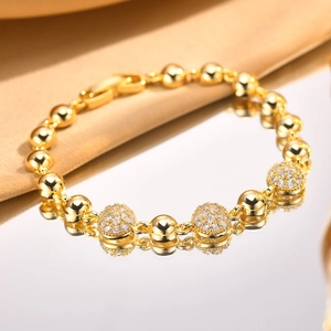 Detail of golden bead bracelet with zircon-encrusted spheres and lobster clasp