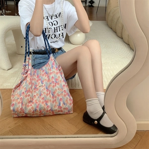 Mirror selfie showing a floral tote bag with pink tulips and blue handles in use