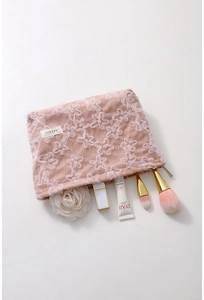 Detail view of pink corduroy makeup bag with floral lace and interior beauty products