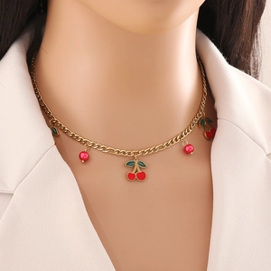 Pendentif cerise mignon sur chaîne double en acier inoxydable doré porté par un modèle