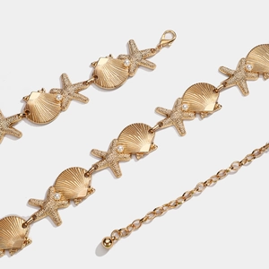 Detail of golden bohemian waist chain with seashell and starfish charms and small pearls