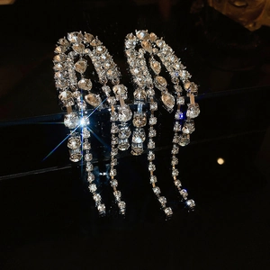 Macro detail of silver tassel earrings featuring sparkling rhinestones on dark background