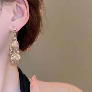Close-up of elegant double water-drop diamond earrings in champagne gold on a female model