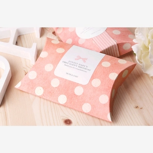 Pink polka dot pillow gift box with bow sticker on a rustic wooden table setup