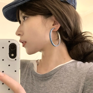 Blue denim fabric round hoop earrings with geometric design worn by a female model