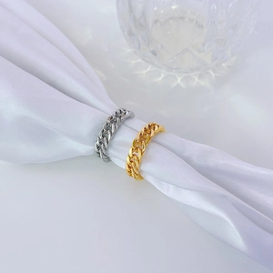 Minimalist 18k gold and silver Cuban chain rings displayed on white silk fabric