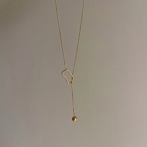 Detail of gold-plated Y-shaped snake chain necklace with hollow circle and bead drop