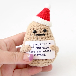 Close-up of handmade crochet potato doll with mini Santa hat and motivational card detail