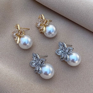 Macro view of gold and silver flower pearl earrings with cubic zirconia on silk cloth