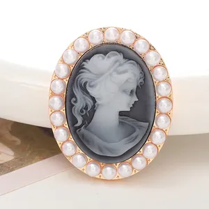 Macro shot of oval cameo brooch with white portrait and pearl border on gold base