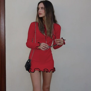 Detailed view of the red long sleeve dress with black ruffled edges and wave knit hem