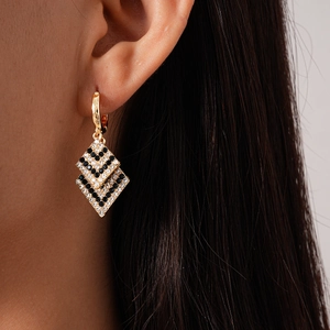 Detail of gold geometric double rhombus earrings with black and white zircon crystals