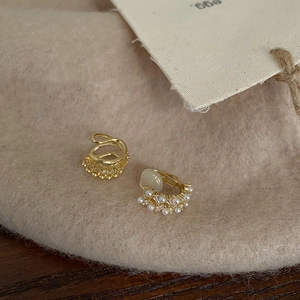 Detail of French vintage gold earrings with pearls and crystals on soft beige felt