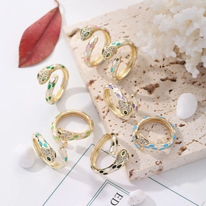 Detailed macro view of colorful enamel snake rings with zircon stones on stone background