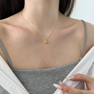 Elegant gold teardrop pendant necklace worn by model showing minimalist jewelry style