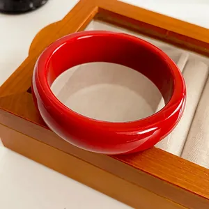 Bracelet jonc minimaliste en résine rouge présenté sur un écrin à bijoux en bois