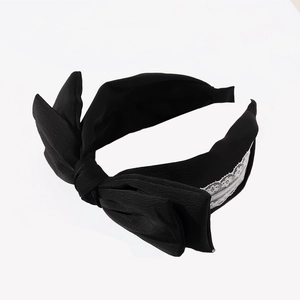 Elegant black fabric headband with a large bow design and delicate white lace detailing